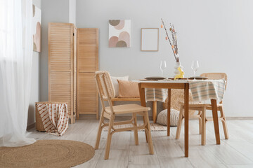 Vase with tree branches and Easter eggs on served table in festive dining room