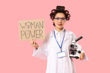 Female Asian chemist holding paper with text WOMAN POWER and microscope on pink background