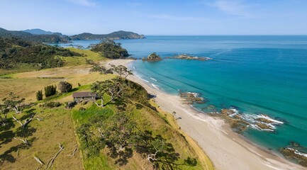 Tranquil Elliot Bay beach scene, New Zealand. Coastal home nestled amongst lush greenery. Aerial view.  Rawhiti, Northland, New Zealand