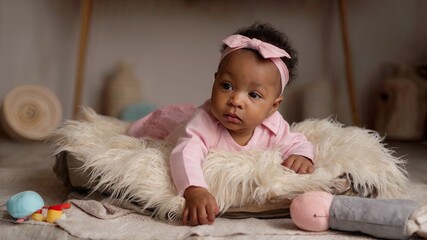 An African American infant resting on a soft surface. 