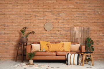 Cozy sofa, stool with cushion and houseplants in interior of living room