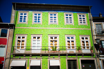 A historic green-tiled house with white-framed windows and balconies in Braga, Portugal.