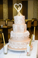 A four-tier pastel pink bridal cake decorated with oriental motifs drawn on fondant and a figure of...