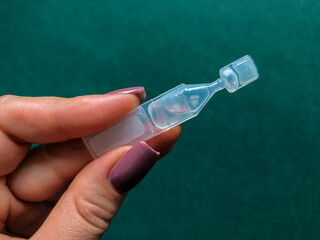 Female hands holding a pack of eye drops. Eye medicine in the form of drops in a disposable package...