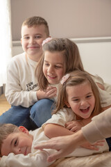 Fototapeta premium four children, sisters and brothers playing with each other, showing family love