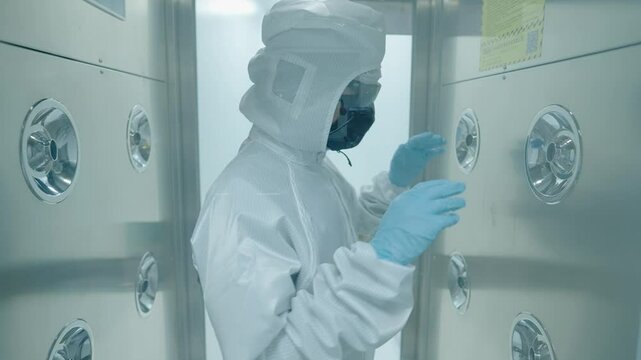 Lab scientist expert in white protection suit walking through the air blowing sanitizing machine to disinfect before working inside the lab, cleaning procedures before entering the lab, disinfection 