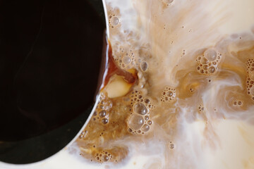 Pouring black coffee into milk for smoother and creamy flavour