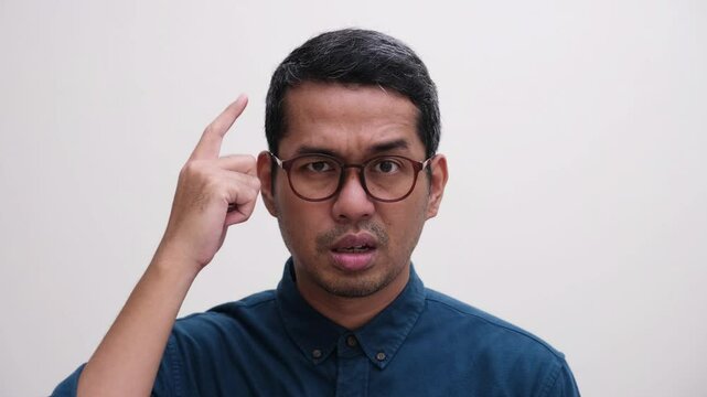 Close up shot of a man pointing his head with cynical face 