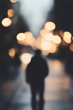 Silhouetted figure walking down a street illuminated by warm bokeh street lights at night : Generative AI