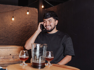 Latin man smiling while talking on cell phone in a bar