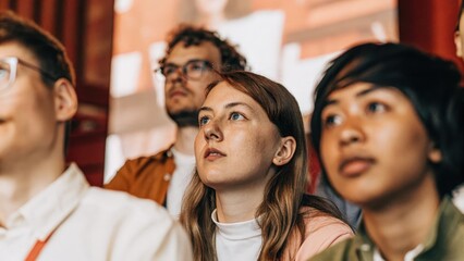 Obraz premium A closeup of an engaged audience watching a holographic presentation on strategic growth with expressions of curiosity and intrigue visible on their faces.