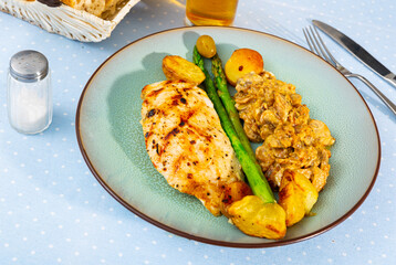 Tasty baked chicken breast with mushrooms in sauce, asparagus and potatoes at plate, nobody