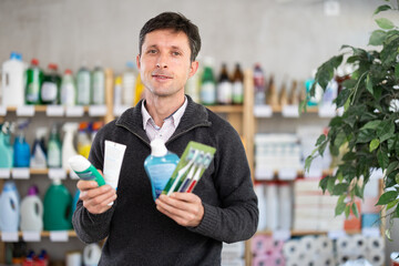 Among shop windows, man buyer leisurely examines goods and make choice dental kit set. Client reads...