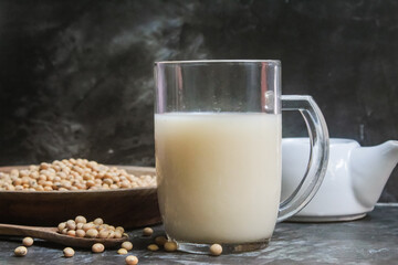 a glass of soy milk with soy beans on the table