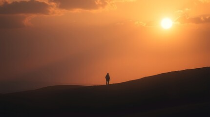 Fototapeta premium Person Walking on Hill at Sunset with Warm Golden Light