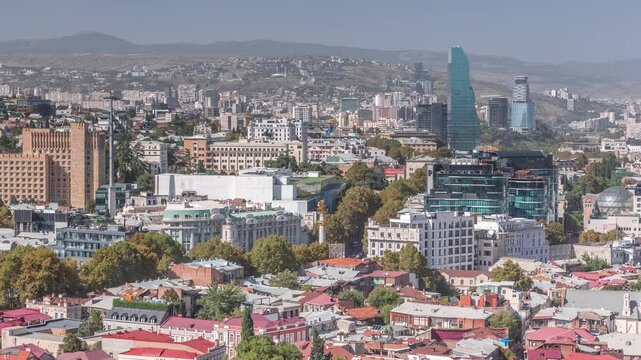 Cityscape panorama with glass tower of hotel in Tbilisi aerial timelapse, skyscrapers of Georgia, located on Rustaveli Avenue. Historic building with clock. View from viewpoint