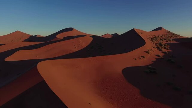 Majestic desert dunes cast lengthening shadows under golden sunset glow