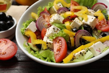Delicious fresh Greek salad in bowl on wooden table, closeup