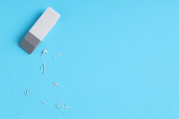 One eraser and scraps on light blue background, top view. Space for text