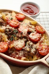 Delicious pasta casserole with cheese, tomatoes, minced meat and thyme in baking dish on white table, closeup