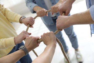 Unity concept. People holding rope together indoors, closeup