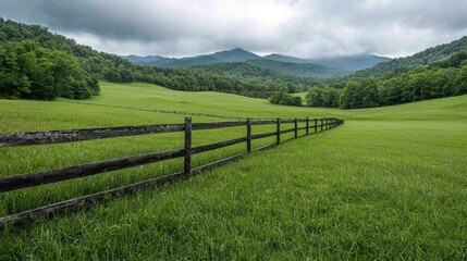 Green valley pasture fence, mountains background, idyllic rural scene