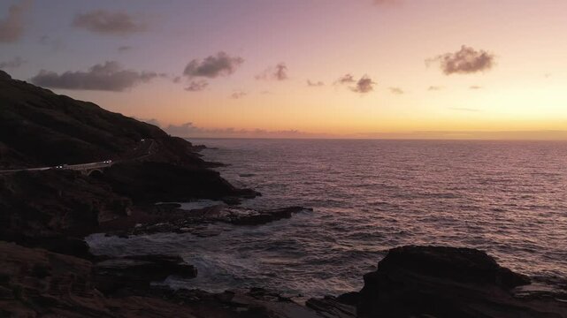 Aerial view of waves crashing on rocks shore in Hawaii at sunrise time