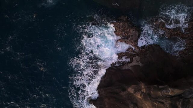 Aerial view of waves crashing on rocks shore in Hawaii