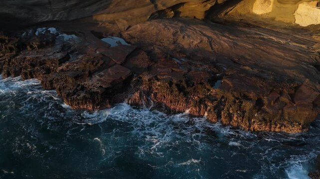 Aerial view of waves crashing on rocks shore in Hawaii