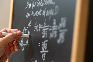 Mathematical operations and trigonometry mathematic formula written with chalk on the blackboard
