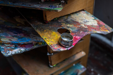 An old palette with oil paints in the artist's studio. Painted background created by a creative person. 