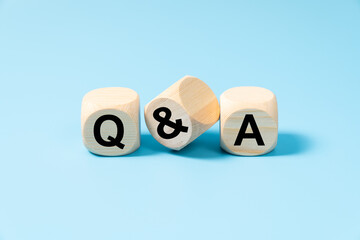 Fototapeta premium Questions and answers concept with three wooden blocks on light blue background with letters Q and A