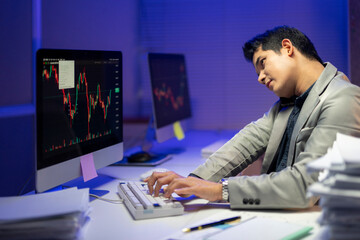 Fototapeta premium A man is sitting at a desk with two computer monitors in front of him