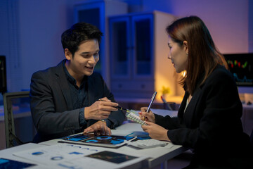 Fototapeta premium A man and a woman are sitting at a table with papers and a laptop