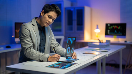 A man is sitting at a desk with a computer monitor and a piece of paper