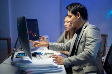 A man and a woman are working on a computer together