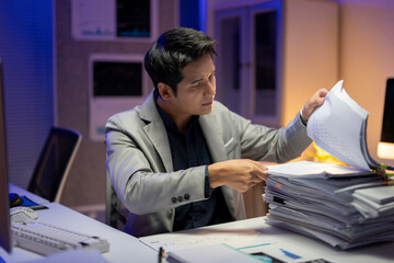 A man is sitting at a desk with a pile of papers in front of him
