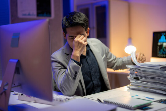 A man is sitting at a desk with a stack of papers in front of him