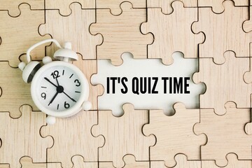 bell clock and wooden puzzle with the word It's Quiz Time. the concept of answering quizzes or quiz...