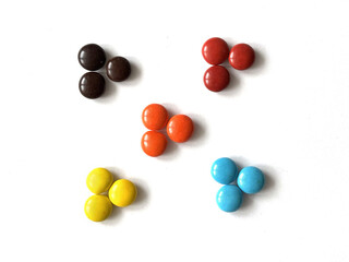 Round multicolored candies isolated on white background arranged in the shape of flowers. Bonbon sweets, dragee 