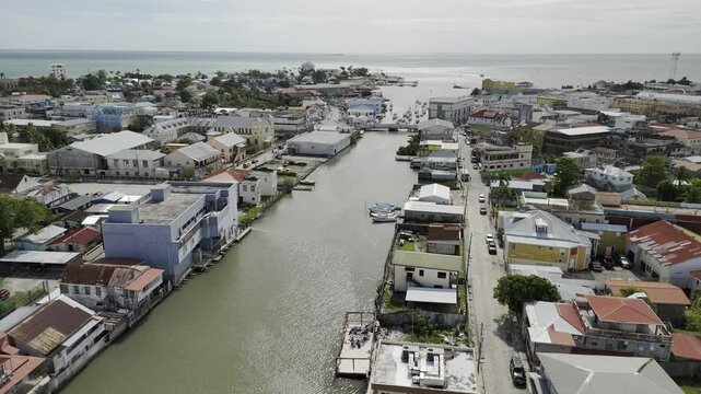 Drone flies down Haulover Creek and over the Swing Bridge on sunny morning in Belize City