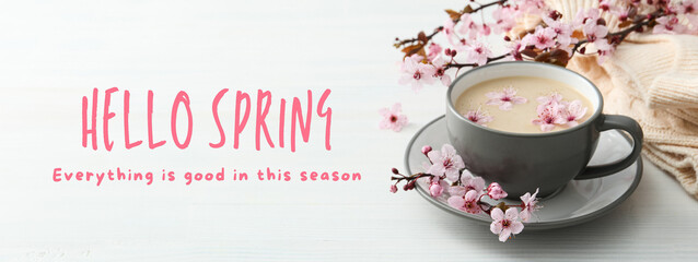 Hello spring, cup of coffee and blooming sakura on a light background with text