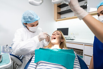 Female dentist examine tooth to Caucasian girl at dental health clinic. 