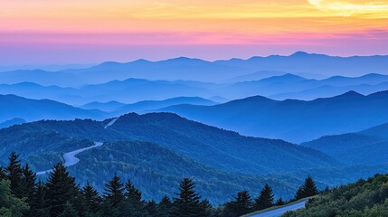 Obraz premium Serene sunset over misty mountain ranges with winding roads and vibrant sky colors