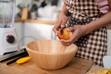 Close up of woman making fresh fruit smoothies in blender in kitchen.