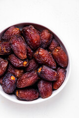 Organic sun dried royal dates in bowl on white background, top view
