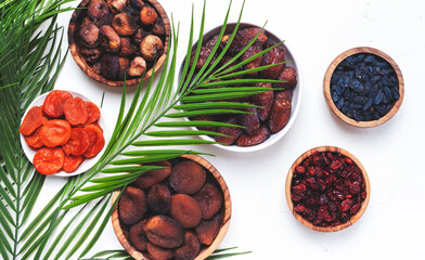 Organic sun dried fruits in bowls on white background. Healthy wholesome snacks instead of sugar and candy, source of vitamins and microelements. Top view