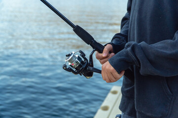 Naklejka premium Close-up of a Boy's Hands Fishing from a Dock on the Lake