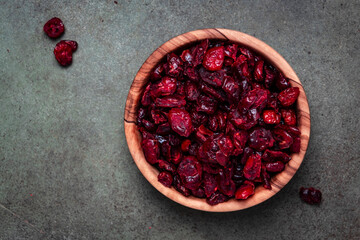 Organic sun dried cranberries in wooden bowl on green background, top view