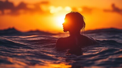 Woman silhouetted in ocean at sunset, tranquil scene